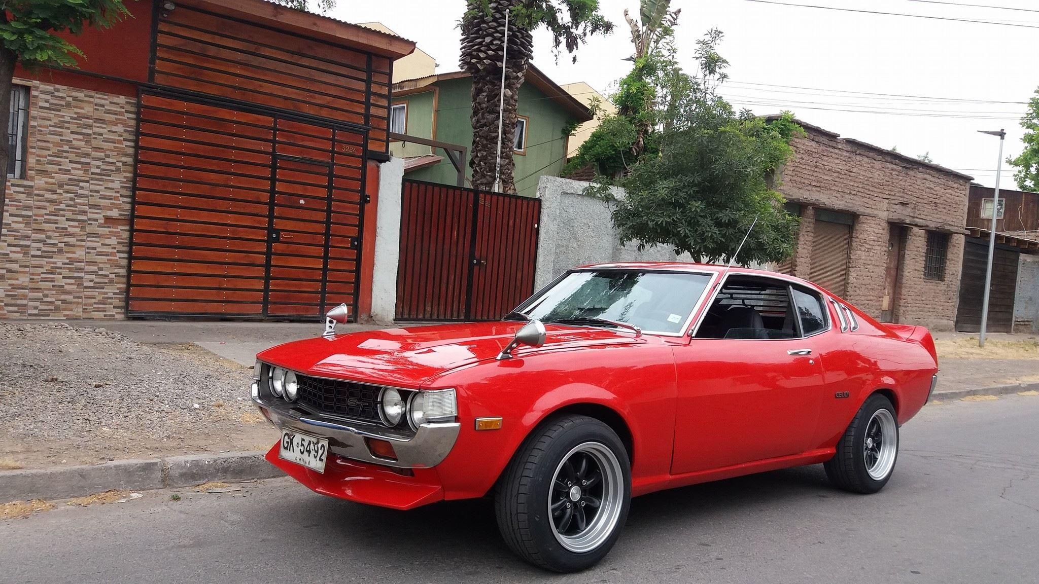 Toyota Celica rojo restaurado estacionado frente al taller